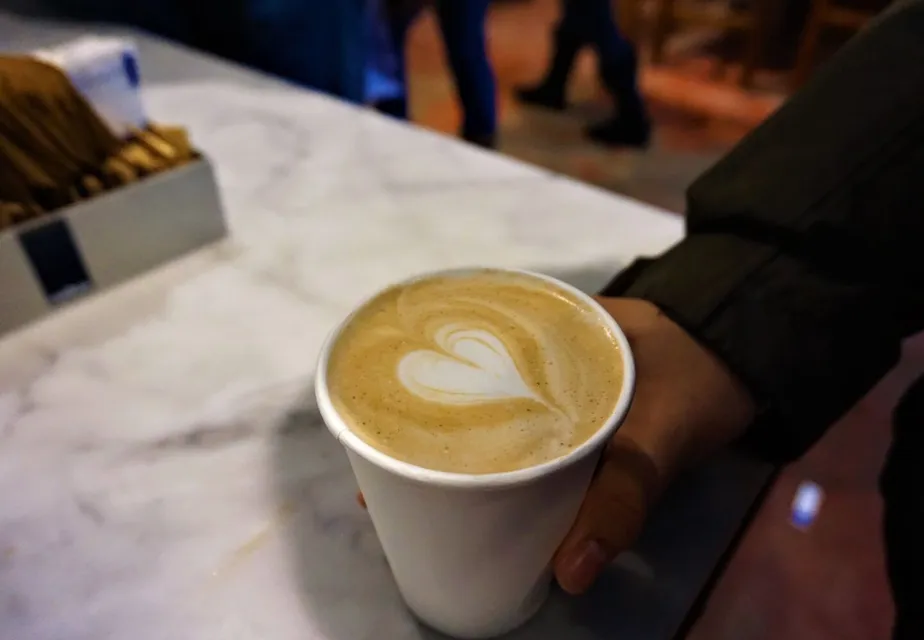 A hand holds a cup of coffee with elegant latte