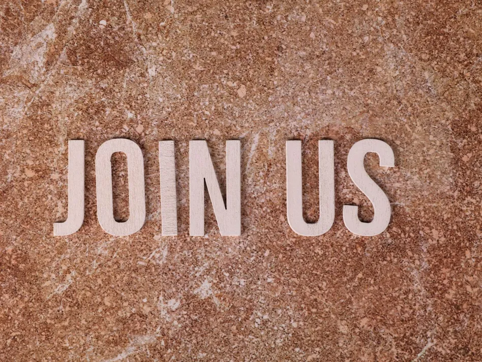Wooden letters spelling 'Join Us' on a brown