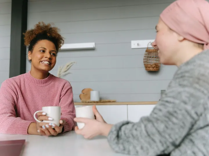 Two women share a joyful coffee moment at home