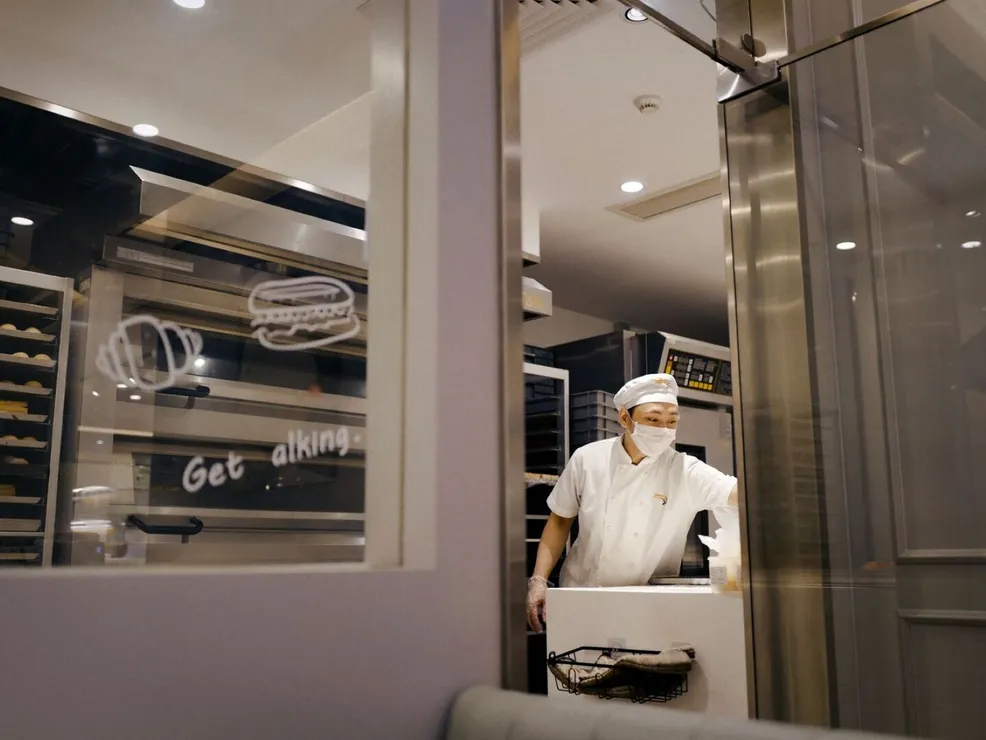 Baker in a commercial kitchen preparing baked goods with pro