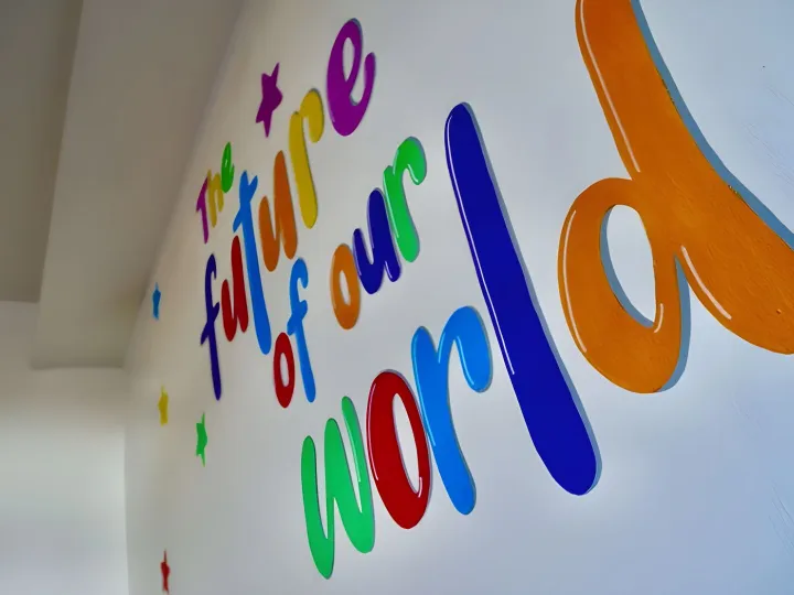 Hand painted wall mural in bright colours reading The future of our world