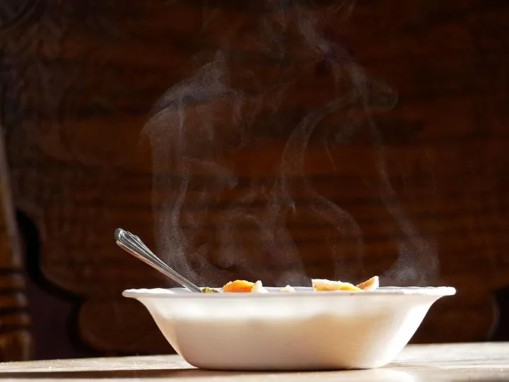 A steaming bowl of soup on a wooden table