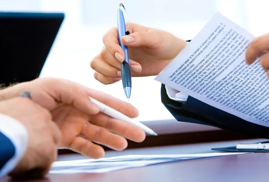 Two people reviewing a printed document at a desk