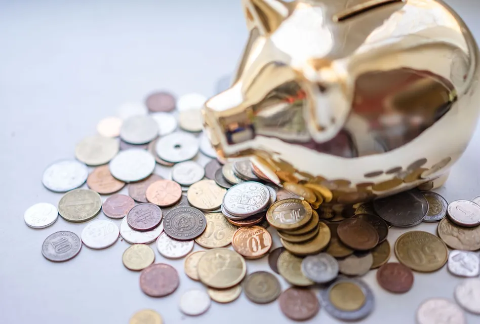 A golden piggy bank surrounded by assorted coins