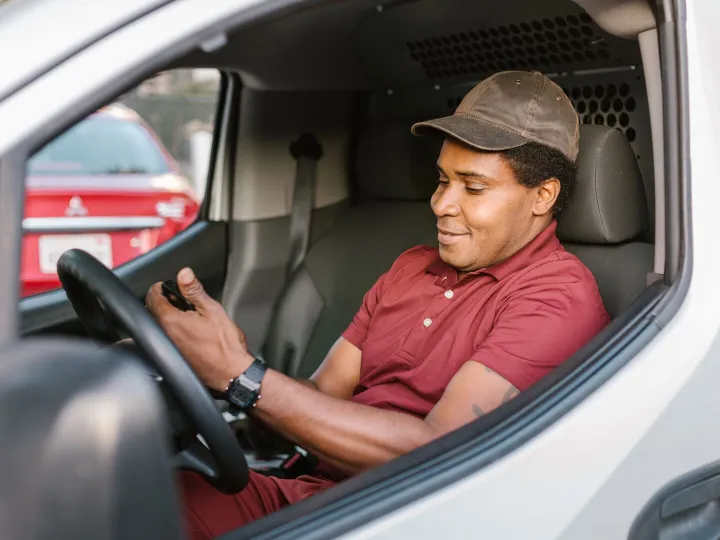 A tradesperson sitting in a work van checking a phone