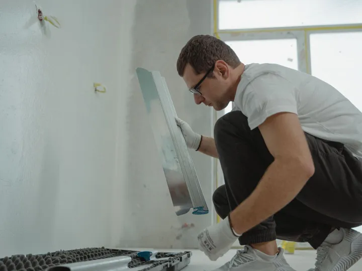 Plasterer using a metal trowel on an interior wall