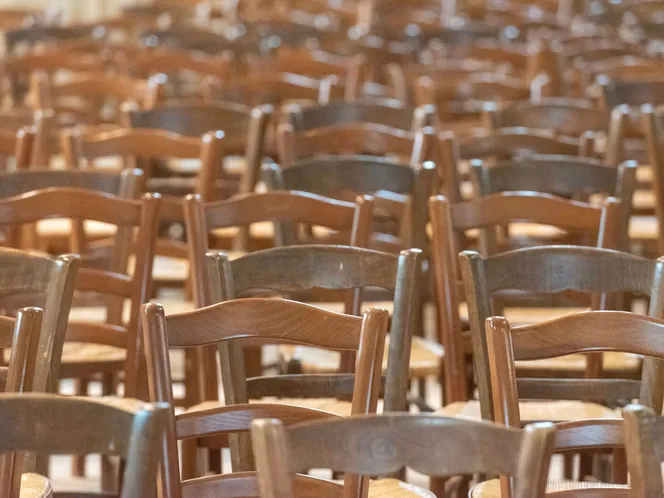 Rows of empty wooden chairs in a quiet church