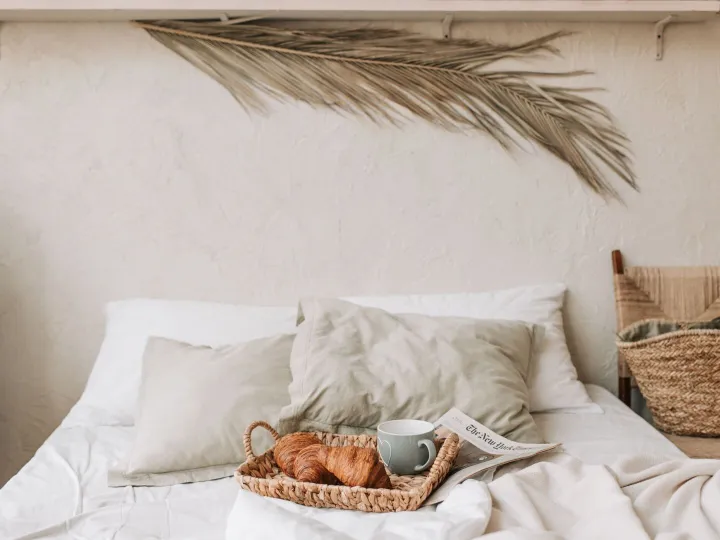 A breakfast tray with croissants and coffee on a freshly made bed