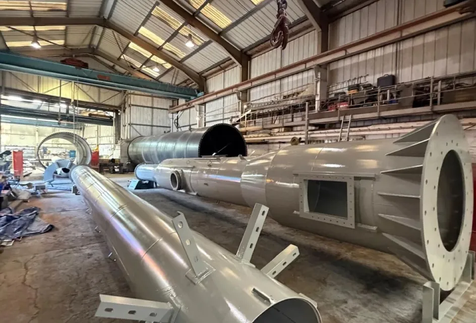 Several topcoated gloss grey steel chimney sections laid out across a workshop floor