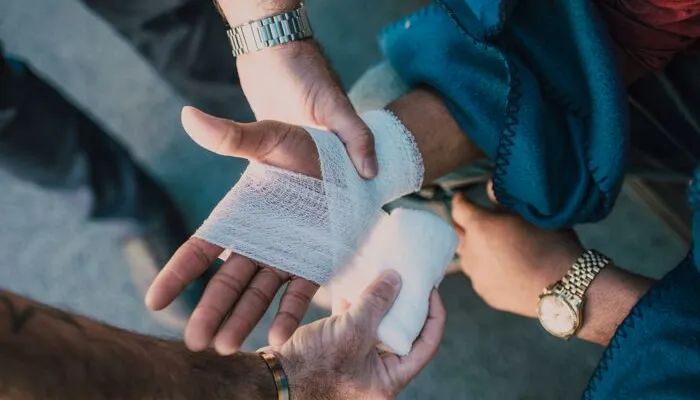 Person Applying Bandage on Another Person's Hand