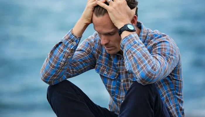 Man in Blue and Brown Plaid Dress Shirt Touching His Hair