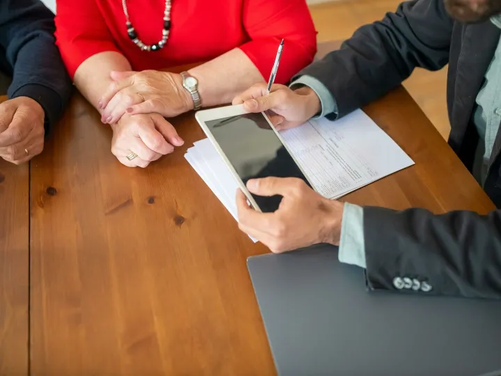 Person in Black Suit Holding White Digital Tablet