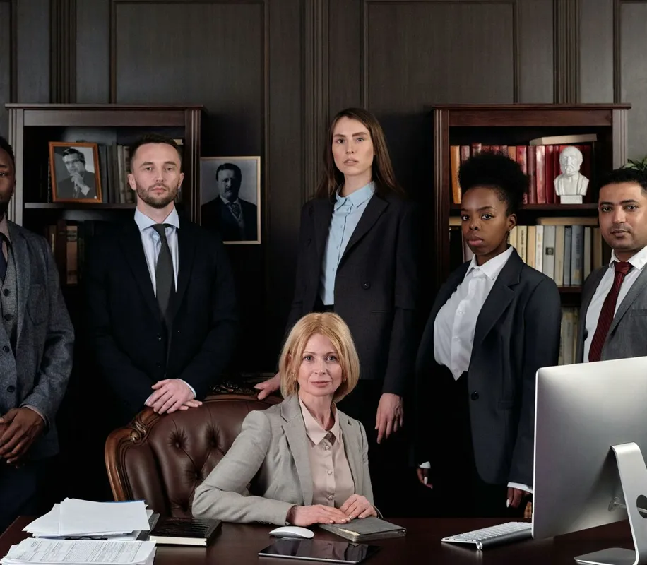 Diverse group of professionals in corporate attire posing confidently in an office environment.