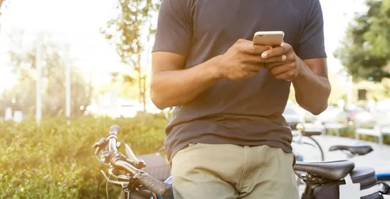 Casual young man leaning on a bike outdoors while