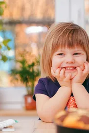 A happy young girl smiling indoors surrounded by