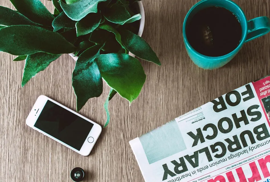 Flat lay arrangement of a coffee mug, newspaper
