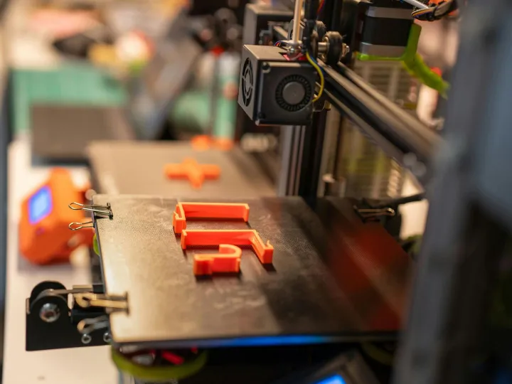 Detailed view of a 3D printer creating an orange p