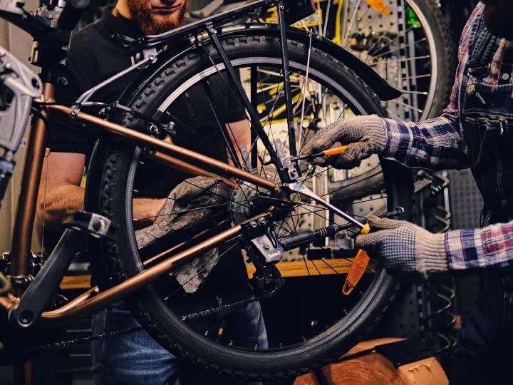 Red head bearded mechanic fixing rear derailleur from a bicy