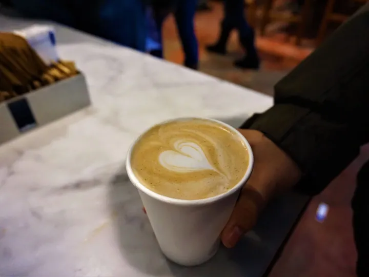 A hand holds a cup of coffee with elegant latte
