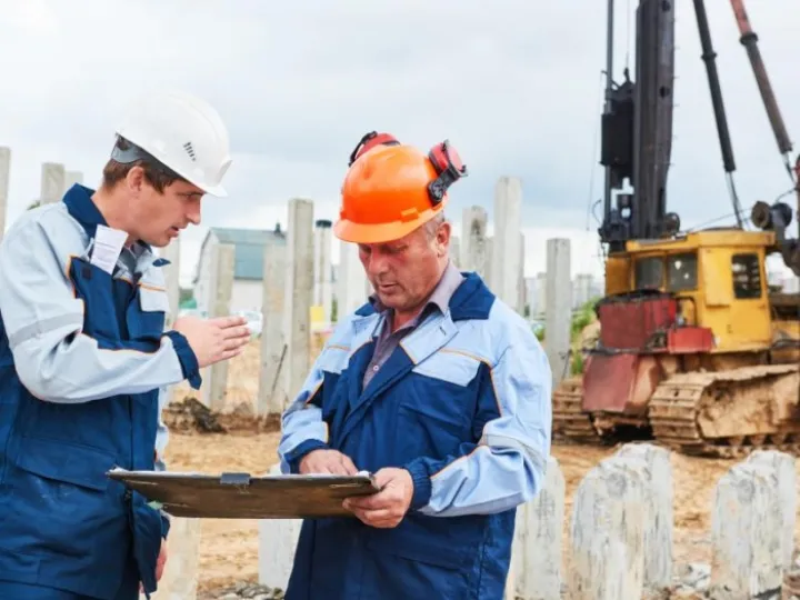 Construction workers  in front of pile driver machine