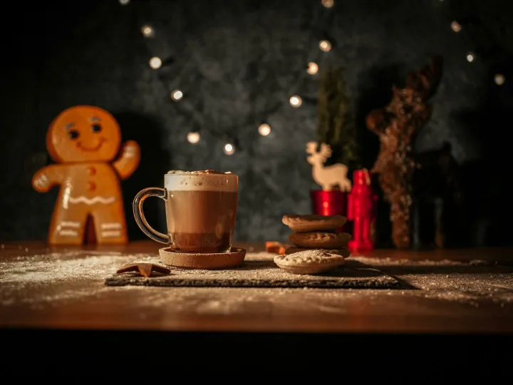 Warm Christmas scene featuring hot chocolate, mince pies, and a gingerbread man with festive lights.