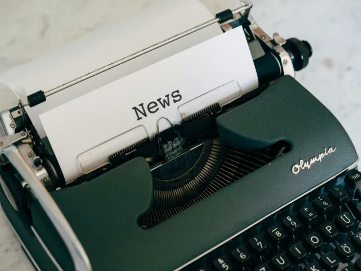 Close-up of an antique typewriter with 'News' on paper.