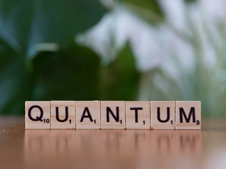 Creative depiction of 'quantum' using wooden letter blocks on a blurred natural background.