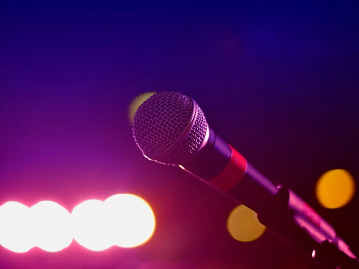 Colorful stage lighting highlights a microphone in a close-up view, perfect for music and performance themes.