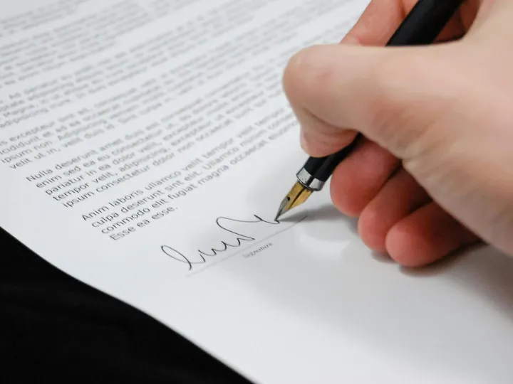 Close-up of a hand signing a legal document with a