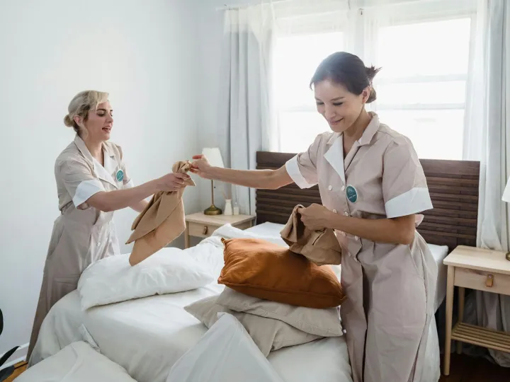 Two female housekeepers in uniform efficiently pre