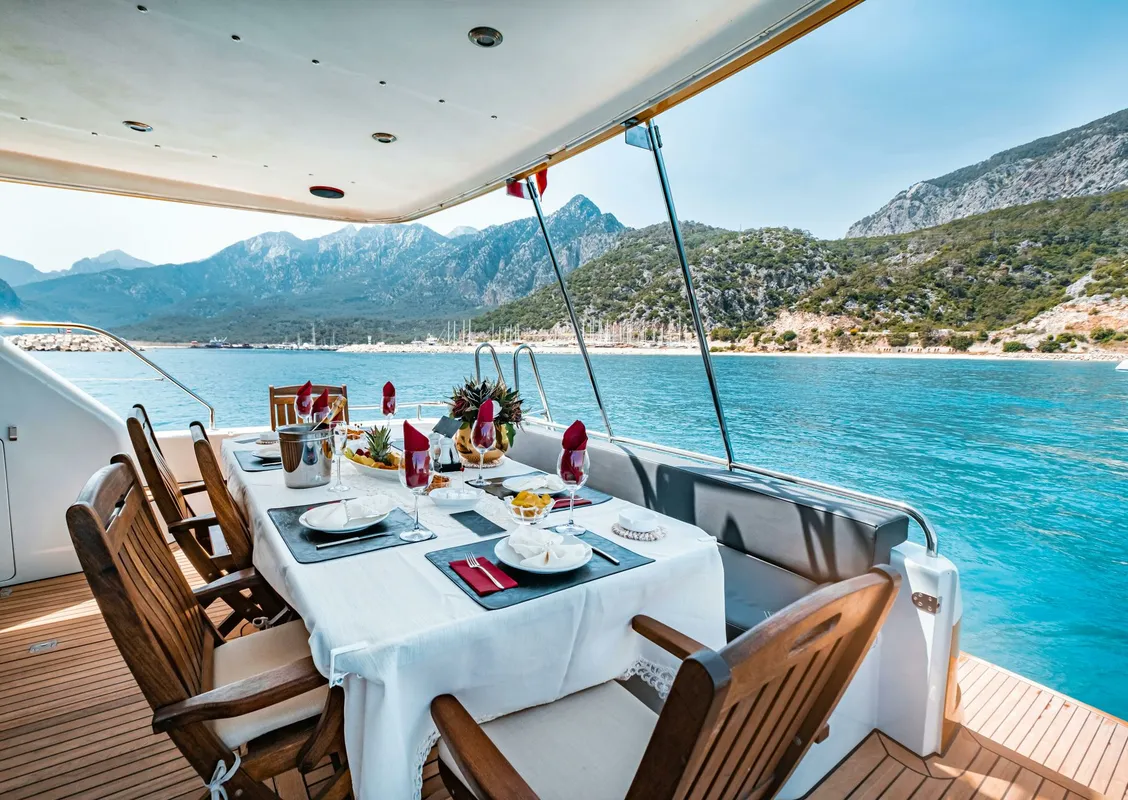 Elegant dining setup on a yacht overlooking Antalya's scenic coast in Türkiye.