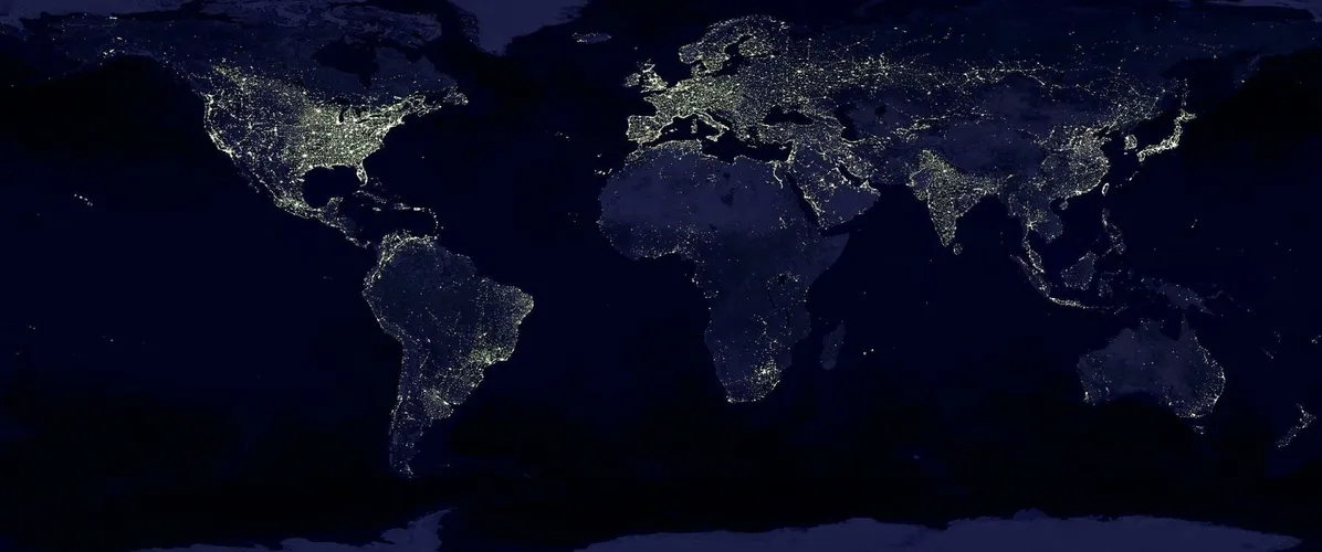 Satellite view of Earth at night with illuminated cities across continents.