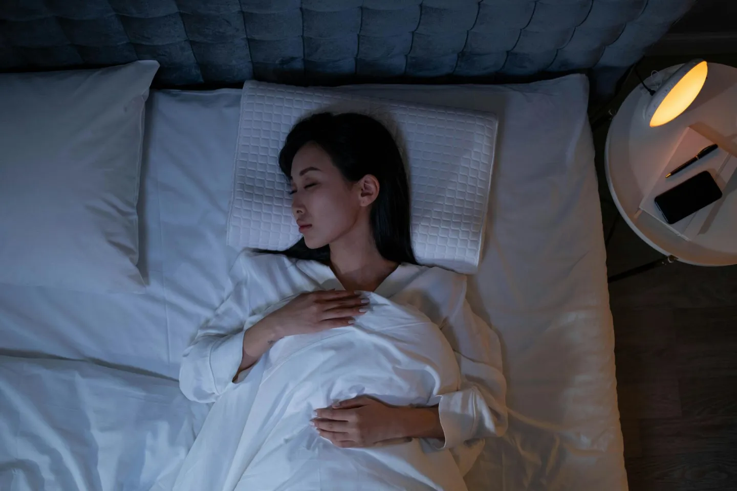Calm and peaceful woman resting in bed under dim