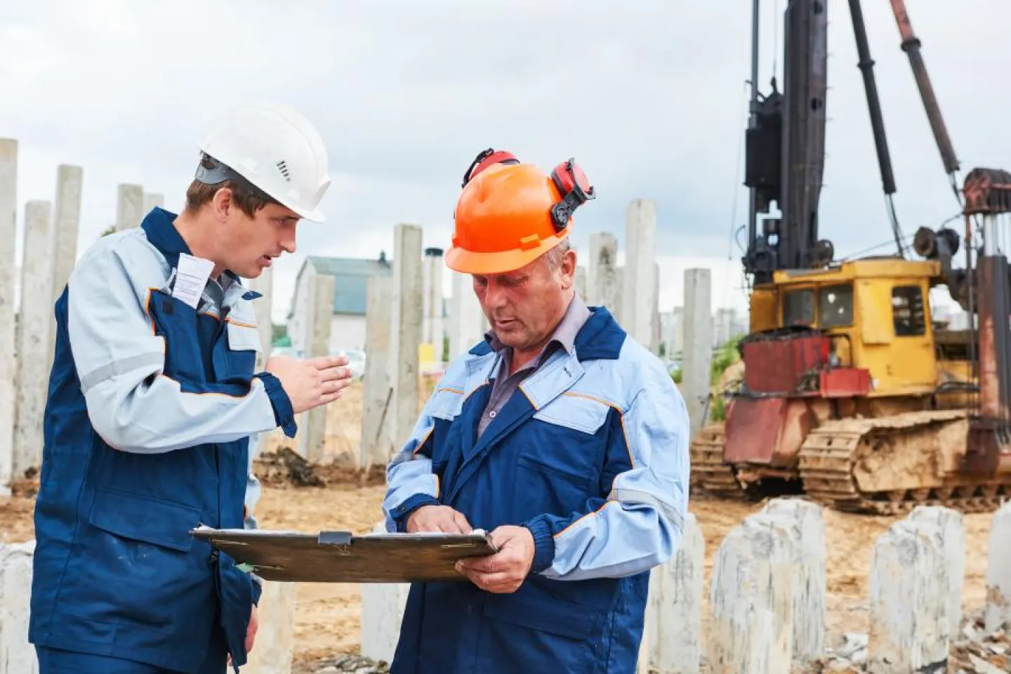 Construction workers  in front of pile driver machine
