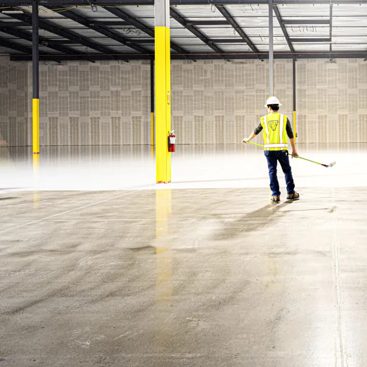 Two workers sweeping a warehouse floor