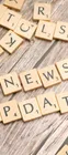 Scrabble tiles spelling 'News Update' on a wooden