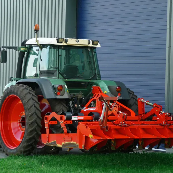 Tractor parked outside a large farm barn