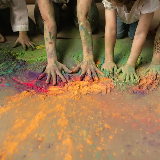 Children's hands mixing brightly coloured craft powder at Messy Church