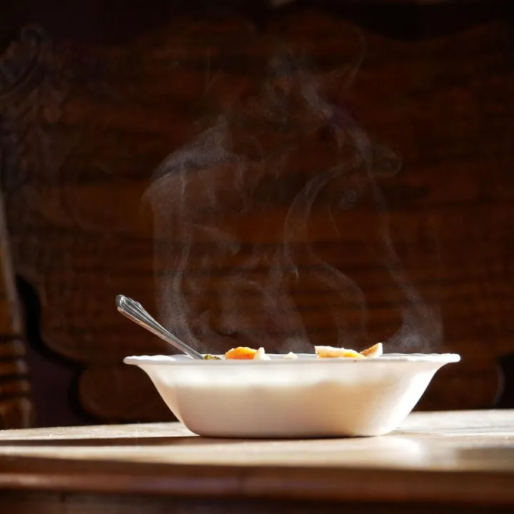 A steaming bowl of soup on a wooden table