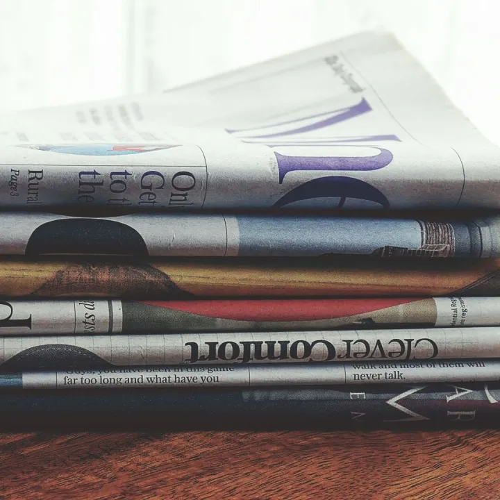 A stack of folded newspapers placed on a wooden