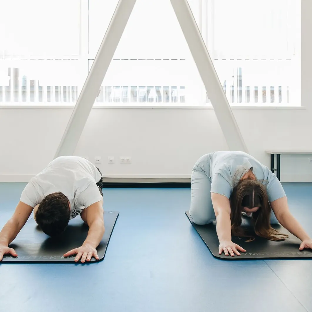 Two people exercising on mats in a modern studio