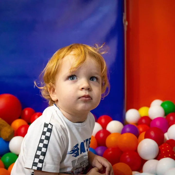 Toddler sitting in a colourful soft play ball pit