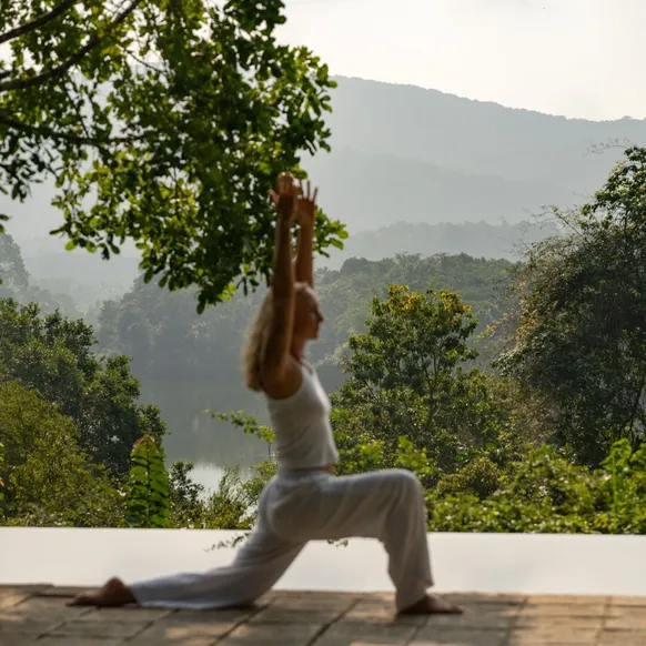 A guest in a yoga pose on the terrace above Wewela Lake at Peacock Hill Sigiriya