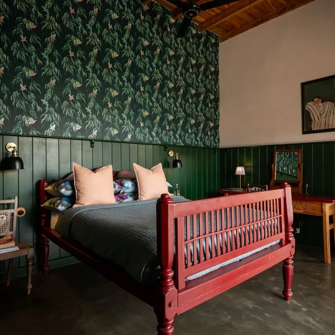 The red bed and writing table against leaf papered walls in the Sigiriya View Suite at Peacock Hill Sigiriya