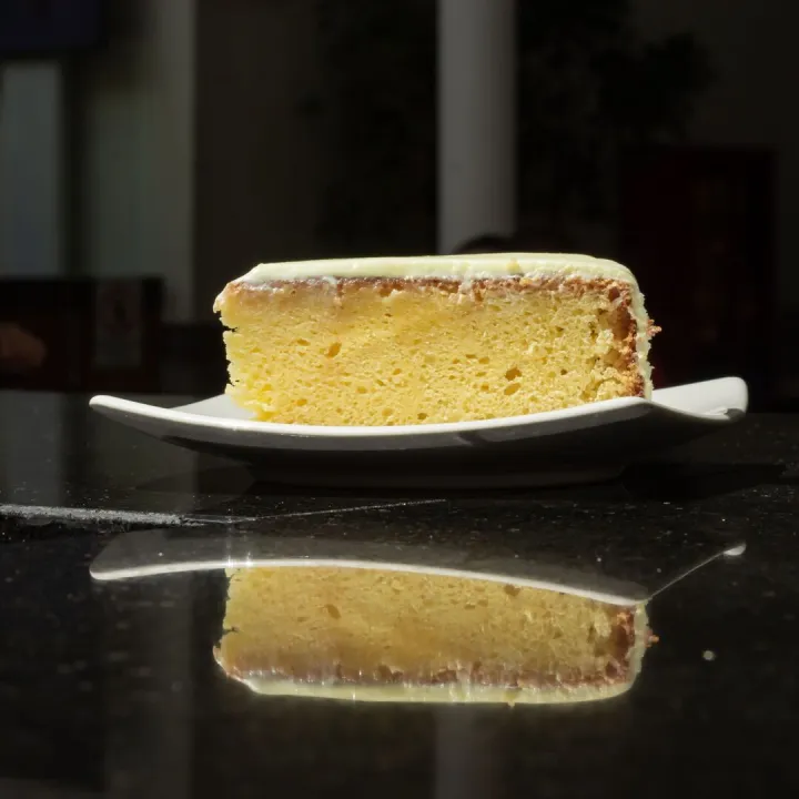 A fresh slice of lemon cake on a white plate
