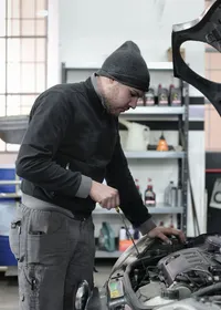 Mechanic checking a car engine in a garage workshop
