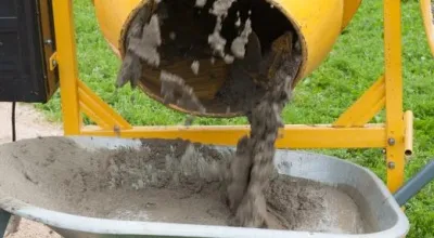 Worker fills cement concrete mixer