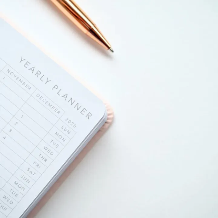 Close-Up Photo of Yearly Planner Beside a Pen 