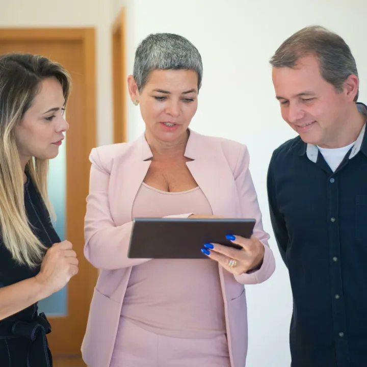 A Couple and a Real Estate Agent Looking at a Digital Tablet