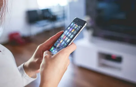 Woman browsing smartphone indoors, highlighting modern technology and communication in a cozy home setting.